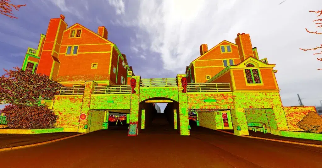 Two large, orange-brick buildings connected by an archway over a road, with vivid yellow, green, and red digital color enhancements.