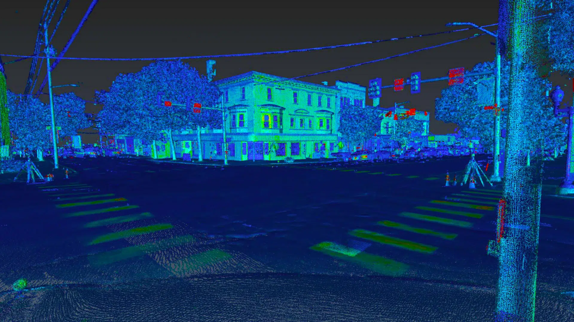 Nighttime city street scene at a corner with a three-story building, crosswalks, and overhead power lines in teal/blue tones (artistic filter).