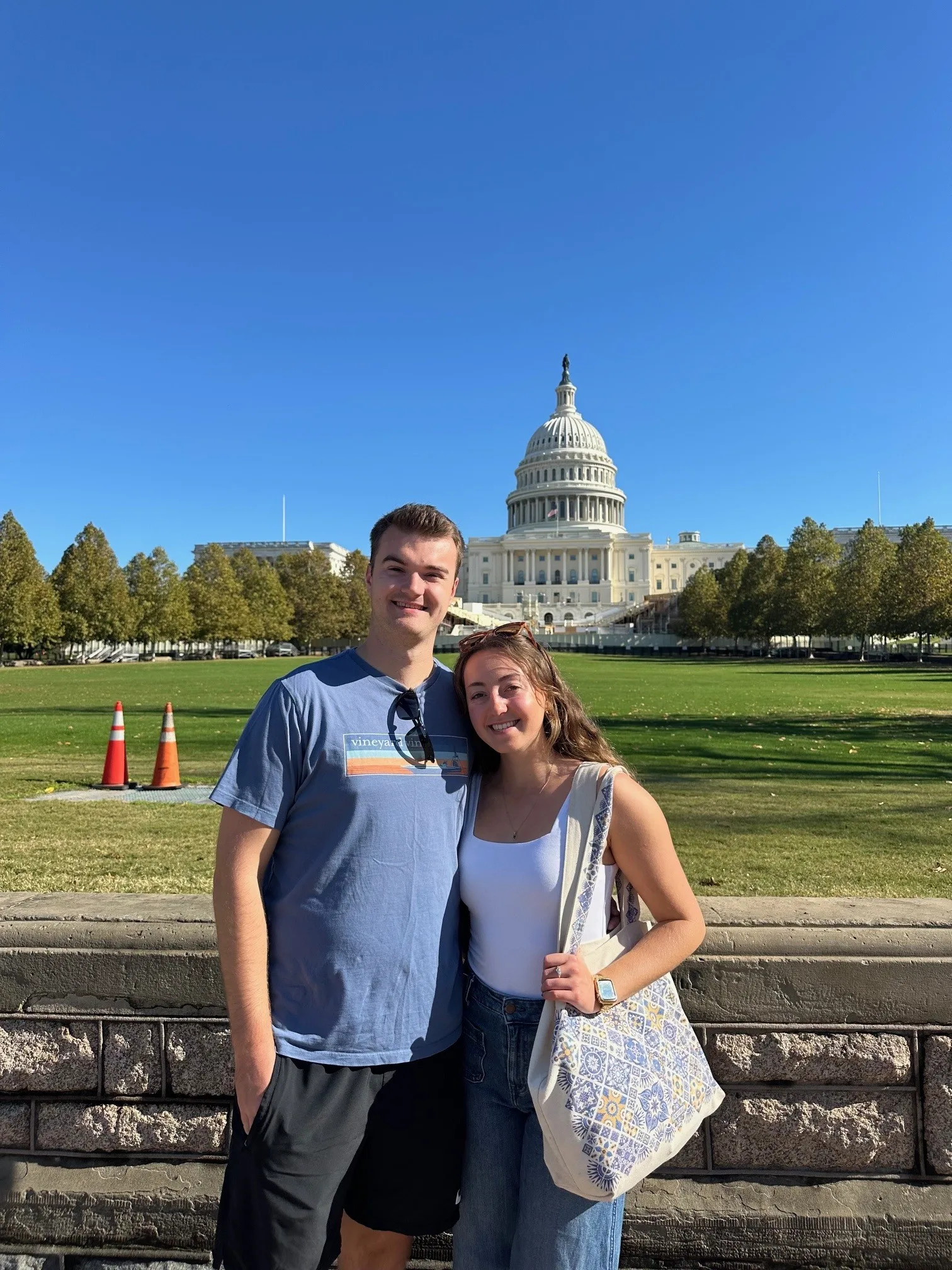 John-Goff-1-1 - Sebago Technics A young man and woman stand smiling in front of the U.S. Capitol building on a sunny day, with green lawns and trees in the background.